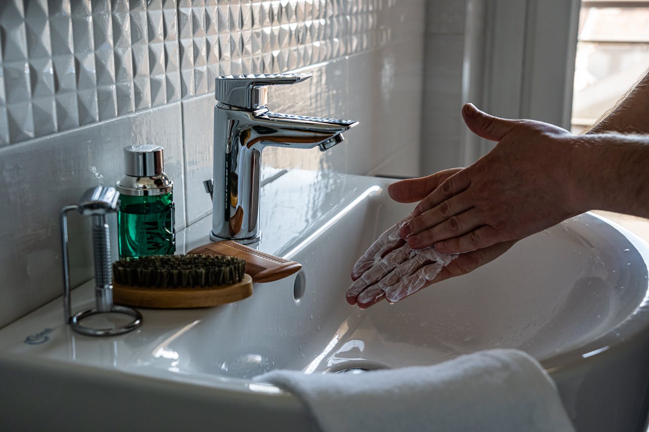 Close-up of hands lathering with soap at a modern bathroom sink with a faucet.